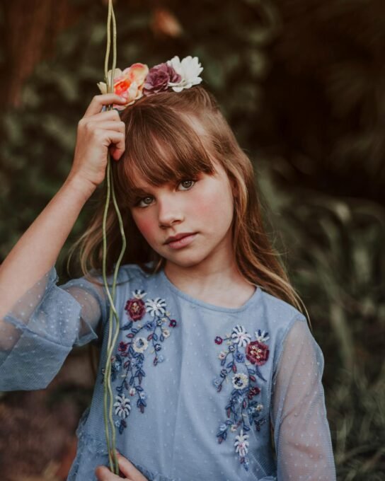 Enchanting portrait of a girl wearing a blue dress and flower crown outdoors.