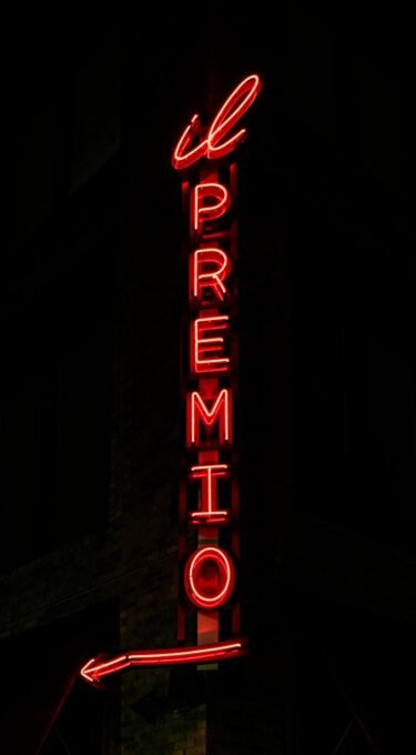 Nighttime neon sign for il Premio restaurant glowing in red against a dark backdrop.