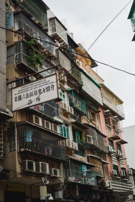 A low-angle view of a densely packed urban apartment building with balconies and air conditioners in Macau.