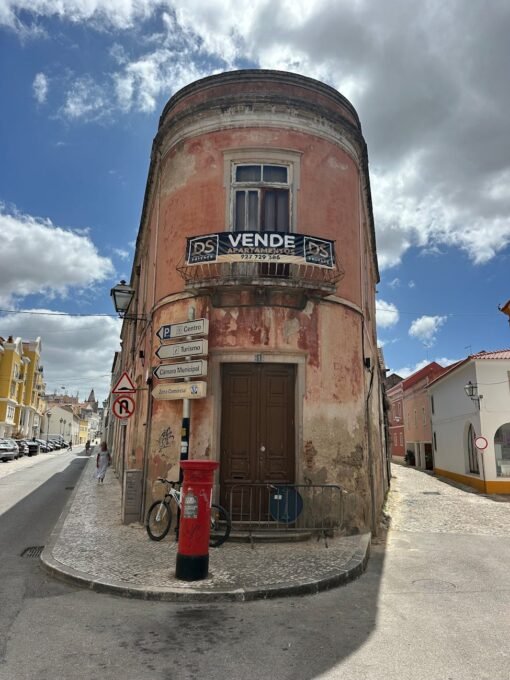 Unique rounded corner building in the historic streets of Torres Vedras, Portugal, captured on a sunny day.