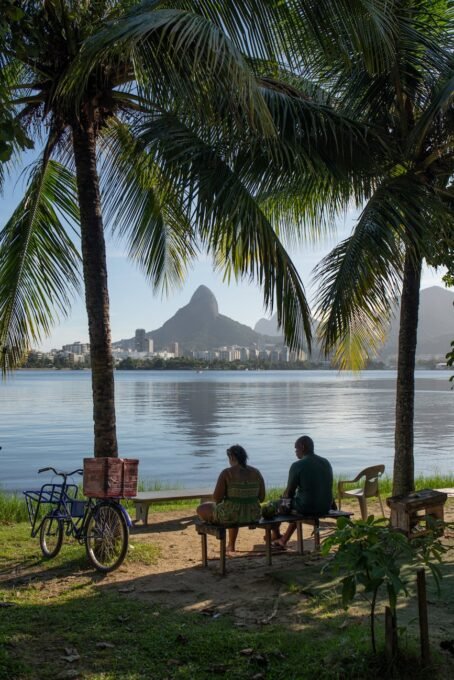 A couple sitting by the lagoon in Rio de Janeiro, enjoying the scenic view of the mountains.