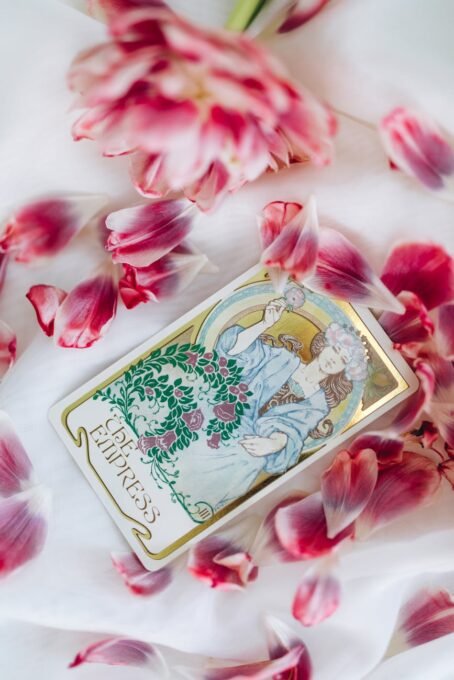 Elegant tarot card surrounded by vibrant pink petals, featuring a mystical feminine illustration, perfect for spiritual themes.